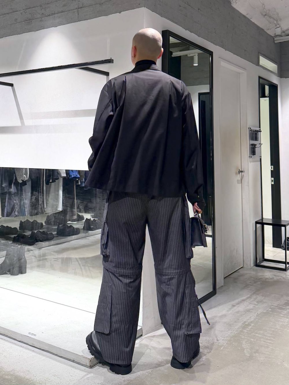 ブラック系のハンドバッグ、ブラック系のドレスシューズ、グレー系のカーゴパンツを着用したメンズの冬コーディネートの4枚目の写真