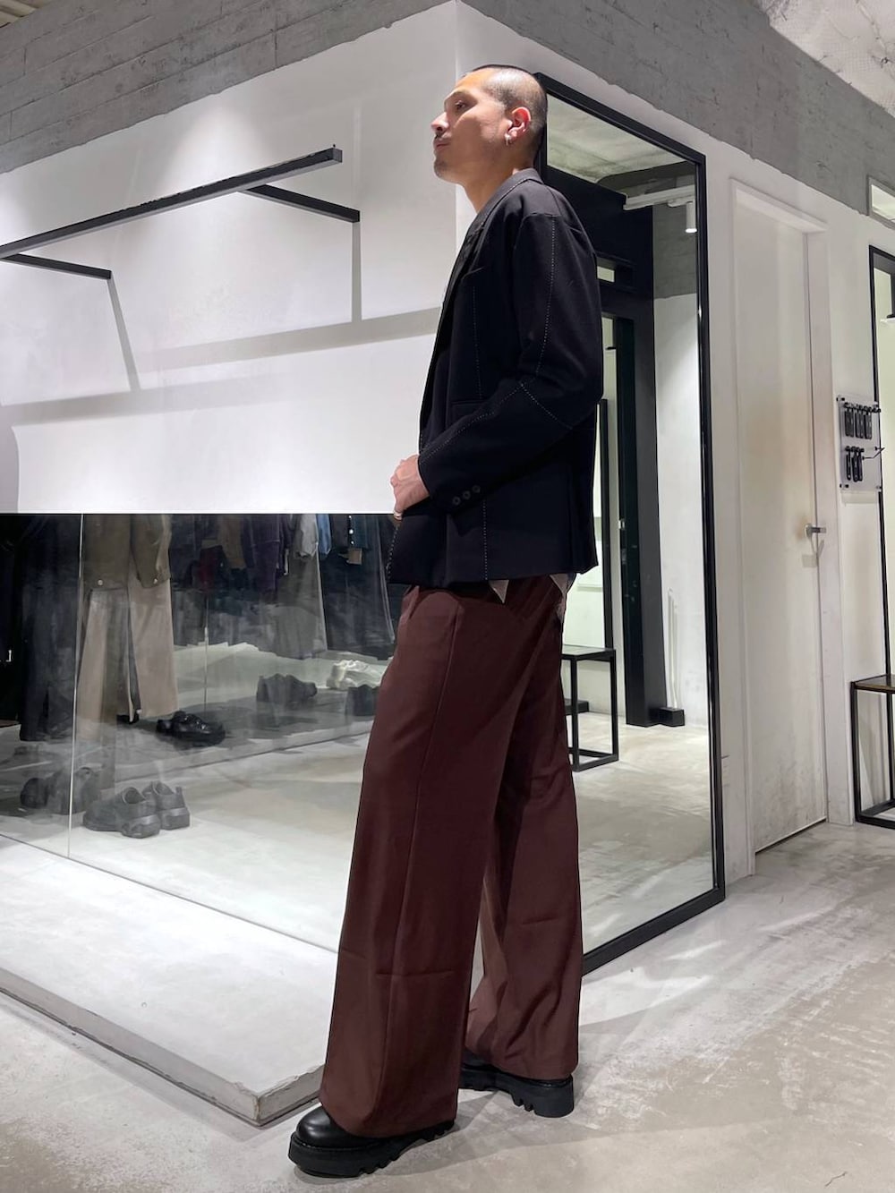 レッド系のスラックス、ブラック系のショルダーバッグ、ブラック系のドレスシューズを着用したメンズの冬コーディネートの2枚目の写真