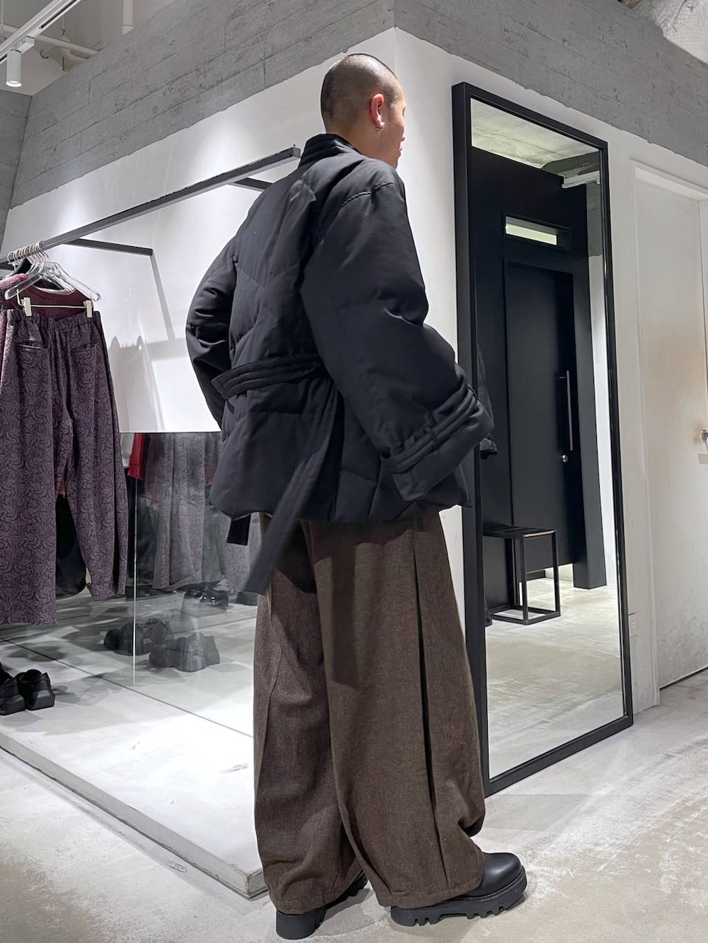 ブラウン系のスラックス、ブラック系のダウンジャケット/コート、ブラック系のドレスシューズを着用したメンズの冬コーディネートの4枚目の写真