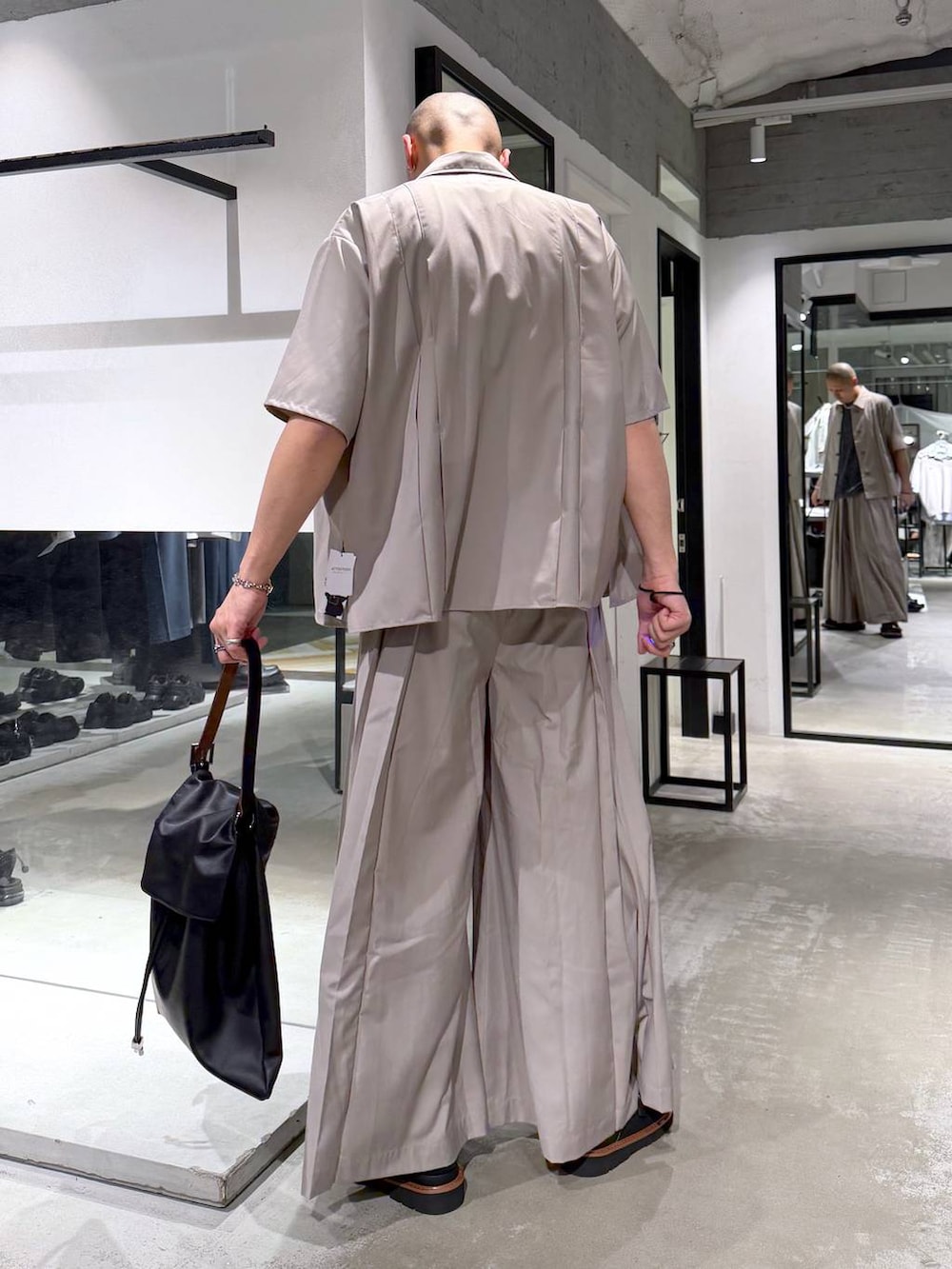 グレー系のTシャツ/カットソー、ブラウン系のサンダル、ブラック系のトートバッグを着用したメンズの春コーディネートの3枚目の写真