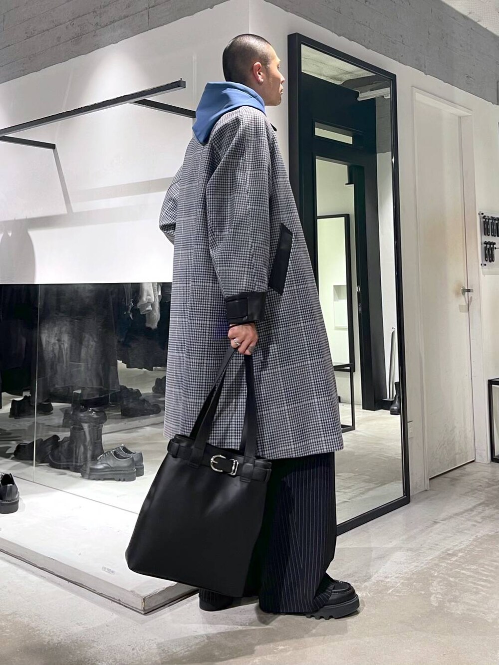 ベージュ系のステンカラーコート、ブラック系のトートバッグ、ブラック系のドレスシューズを着用したメンズの秋コーディネートの4枚目の写真