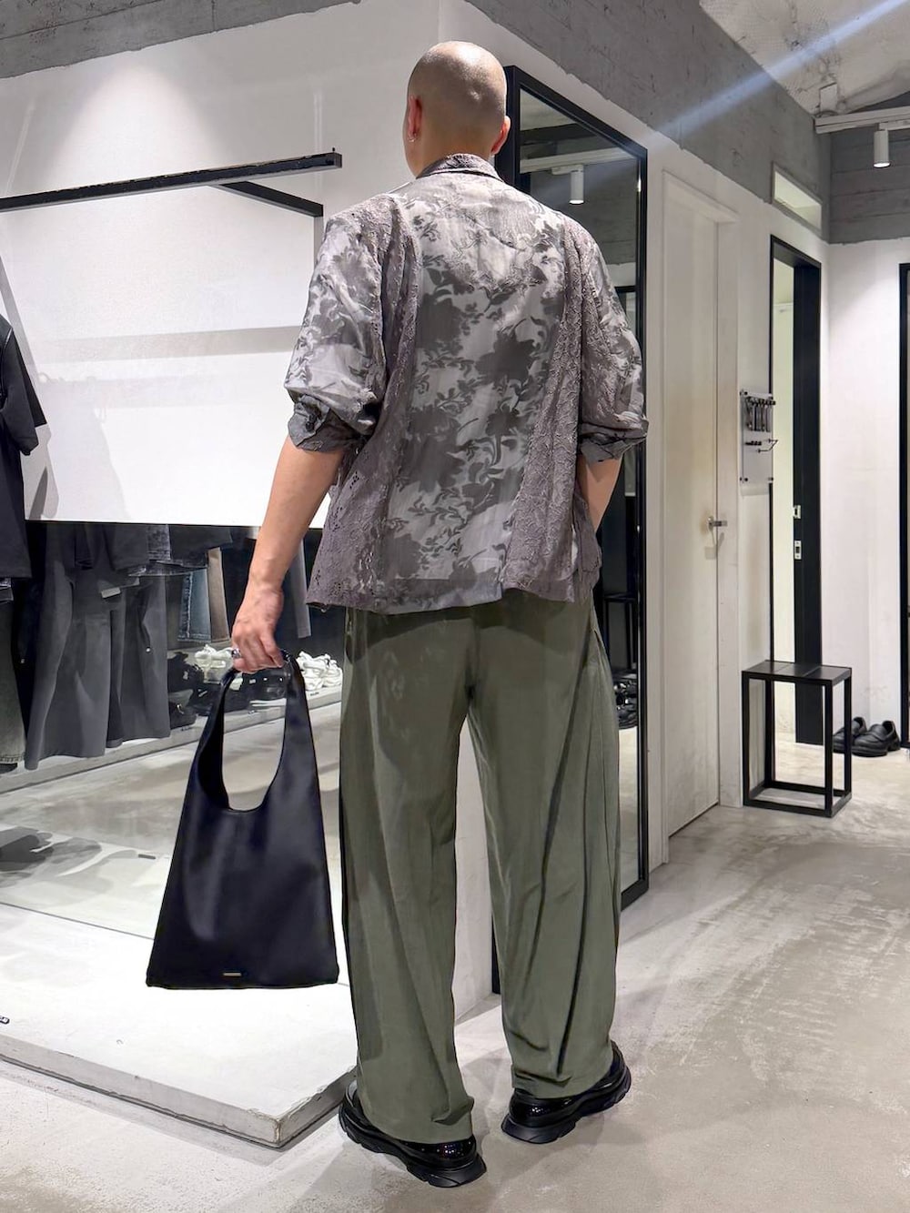 ブラック系のトートバッグ、ホワイト系のTシャツ/カットソー、グリーン系のスラックスを着用したメンズの夏コーディネートの3枚目の写真