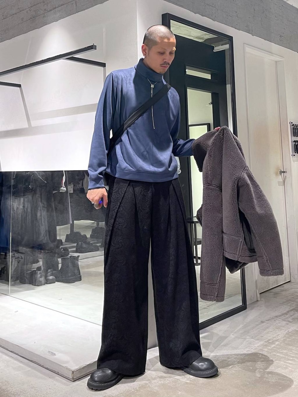 グレー系のブルゾン、ブラック系のブーツ、ブラック系のショルダーバッグを着用したメンズの冬コーディネートの5枚目の写真