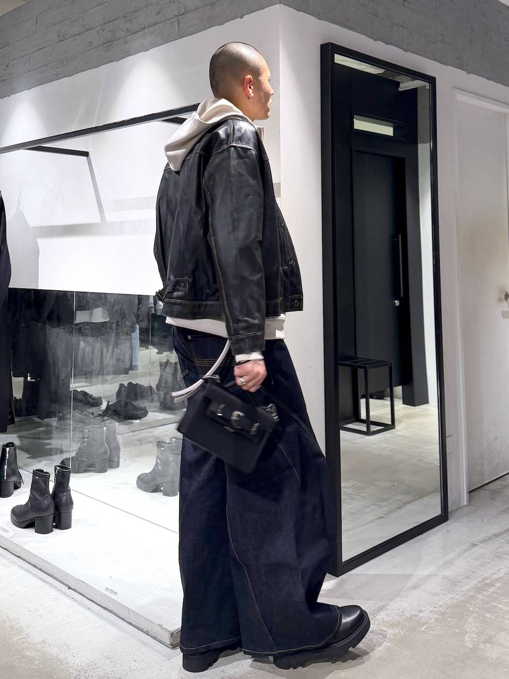 グレー系のパーカー、ブラック系のドレスシューズ、ブラック系のハンドバッグを着用したメンズの冬コーディネートの4枚目の写真