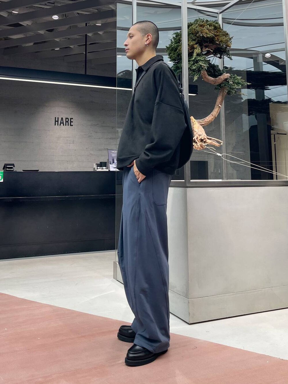 ブラック系のローファー、ブルー系のスウェットパンツ、ブラック系のショルダーバッグを着用したメンズの秋コーディネートの2枚目の写真