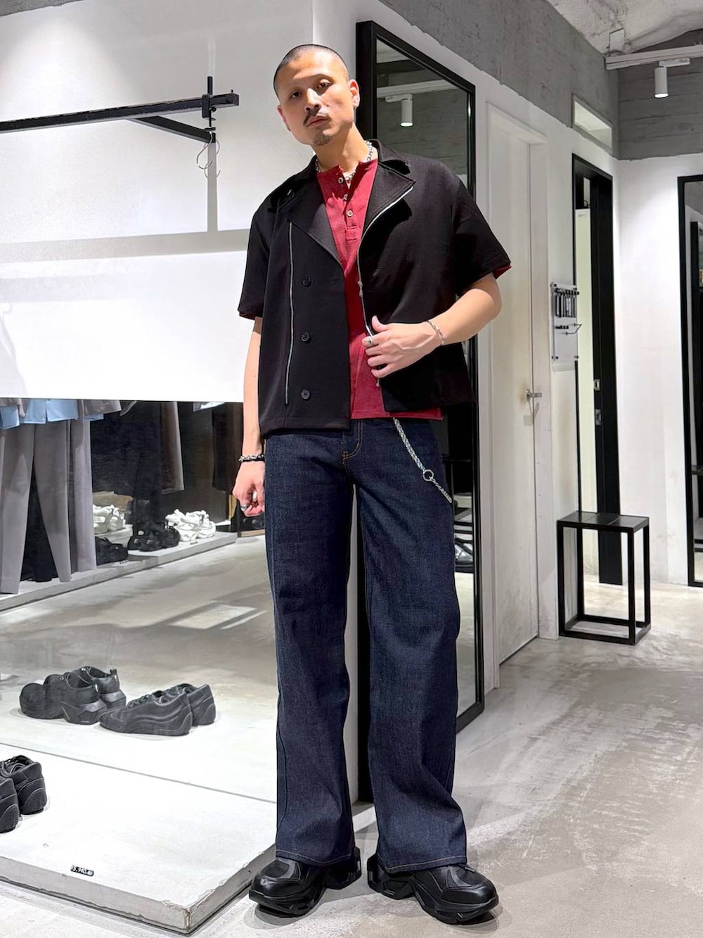 ブラック系のスニーカー、レッド系のTシャツ/カットソー、ブルー系のデニムパンツを着用したメンズの夏コーディネートの2枚目の写真