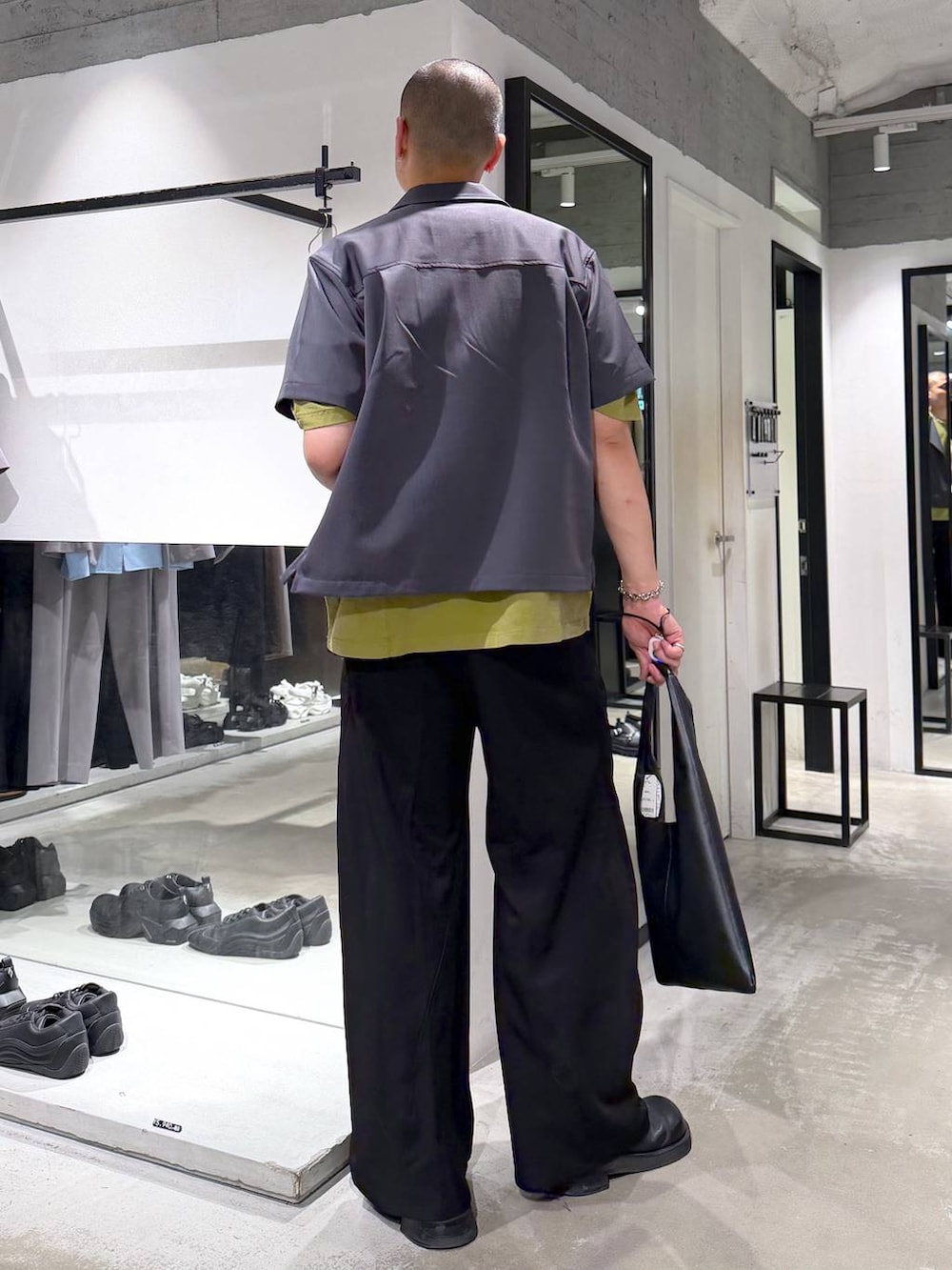 イエロー系のTシャツ/カットソー、ブラック系のトートバッグ、ブラック系のスラックスを着用したメンズの夏コーディネートの3枚目の写真