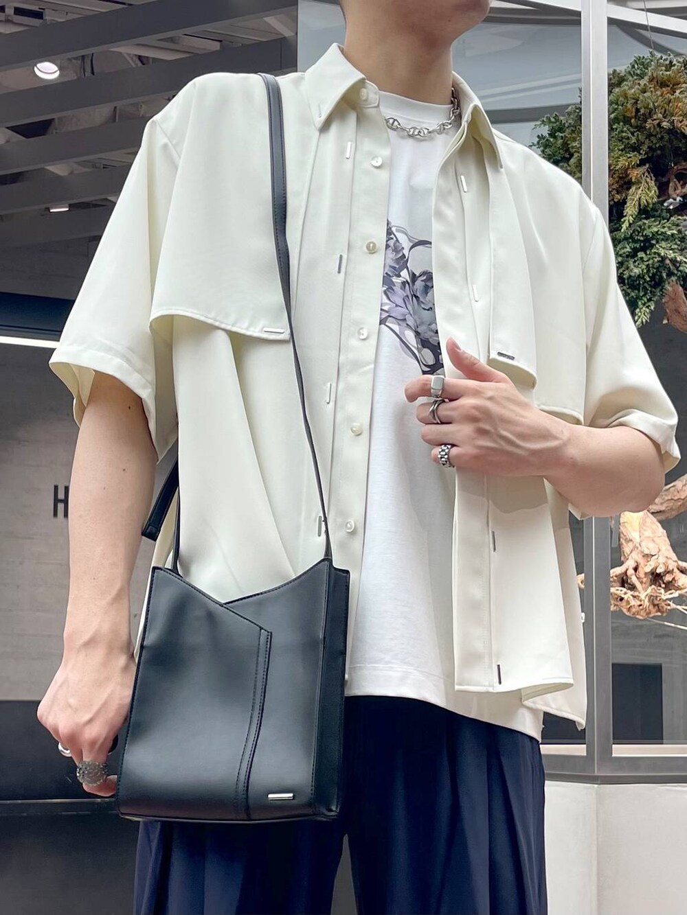 ブラック系のショルダーバッグ、ブラック系のサンダル、ブルー系のスラックスを着用したメンズの夏コーディネートの2枚目の写真