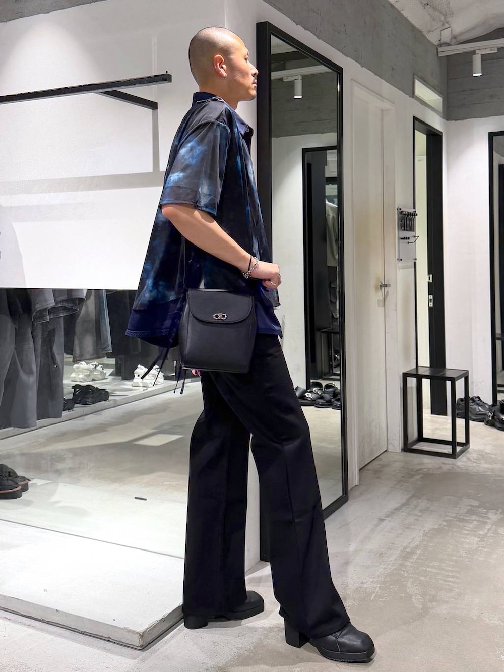 ブラック系のショルダーバッグ、ホワイト系のTシャツ/カットソー、ブラック系のサンダルを着用したメンズの夏コーディネートの4枚目の写真
