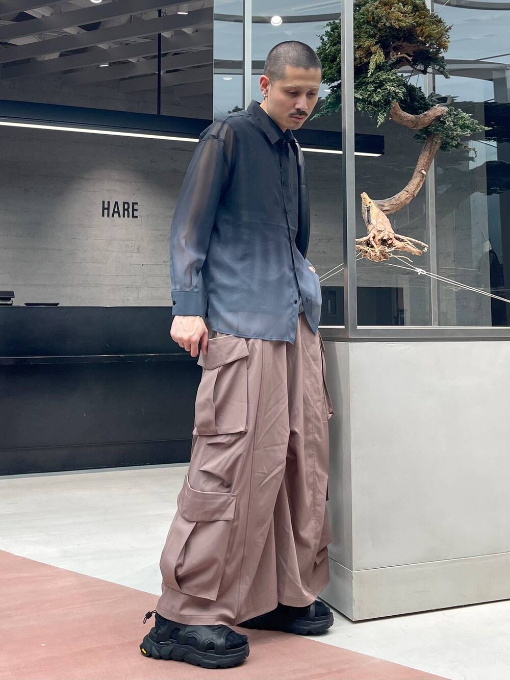 ブラック系のトートバッグ、ピンク系のカーゴパンツ、ブラック系のサンダルを着用したメンズの春コーディネートの2枚目の写真