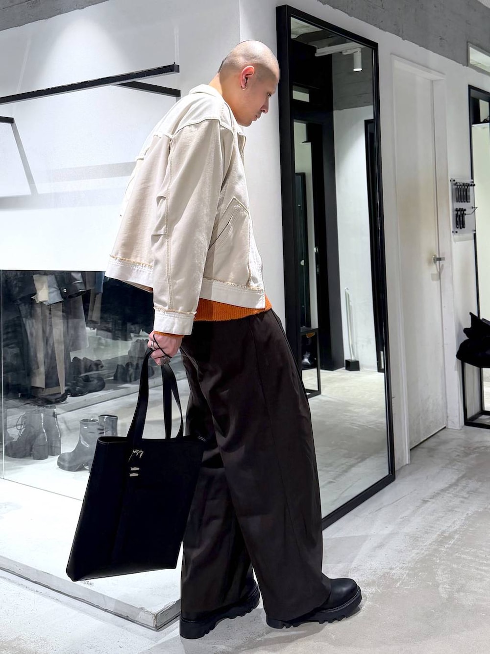 ブラック系のドレスシューズ、ブラック系のトートバッグ、オレンジ系のニット/セーターを着用したメンズの冬コーディネートの4枚目の写真