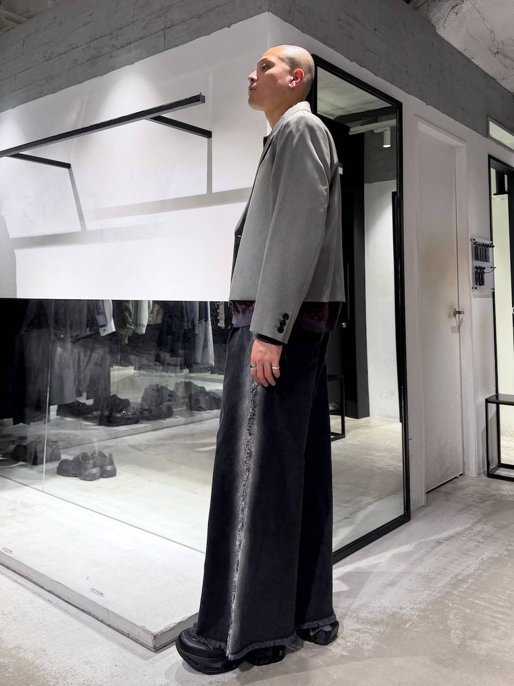 ブラック系のスニーカー、ブラック系のハンドバッグ、ブラック系のデニムパンツを着用したメンズの冬コーディネートの2枚目の写真