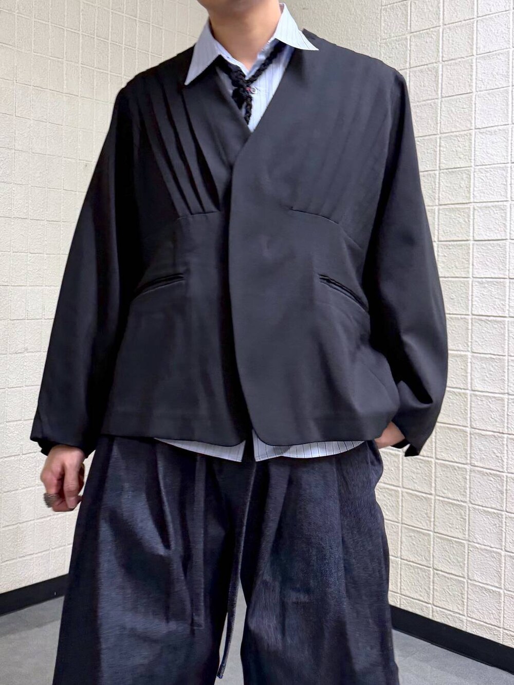 ブラック系のノーカラージャケット、ブルー系のデニムパンツを着用したメンズの春コーディネートの7枚目の写真