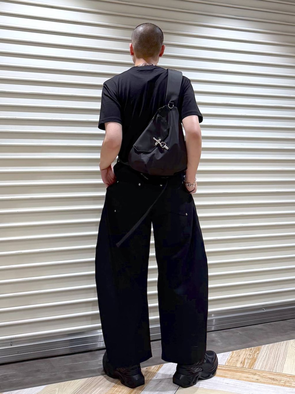 ブラック系のスラックス、ブラック系のTシャツ/カットソー、ブラック系のスニーカーを着用したメンズの夏コーディネートの3枚目の写真