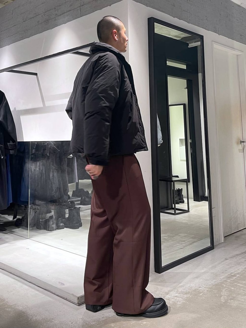 グレー系のニット/セーター、ブラック系のダウンジャケット/コート、レッド系のスラックスを着用したメンズの冬コーディネートの4枚目の写真