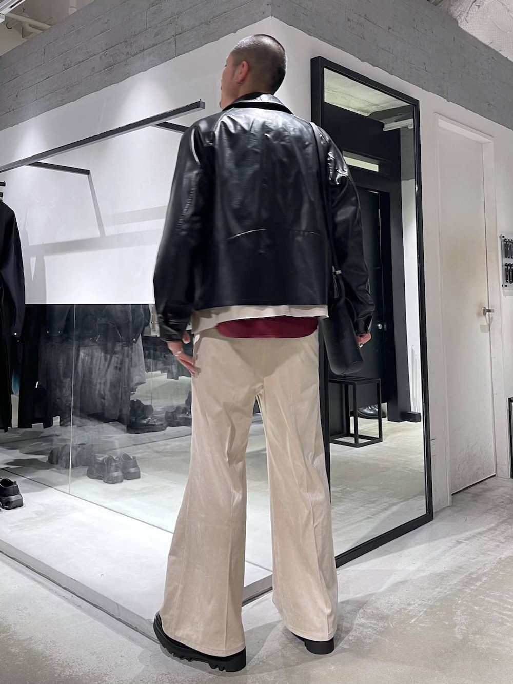 ベージュ系のスラックス、レッド系のシャツ/ブラウス、ブラック系のショルダーバッグを着用したメンズの冬コーディネートの3枚目の写真