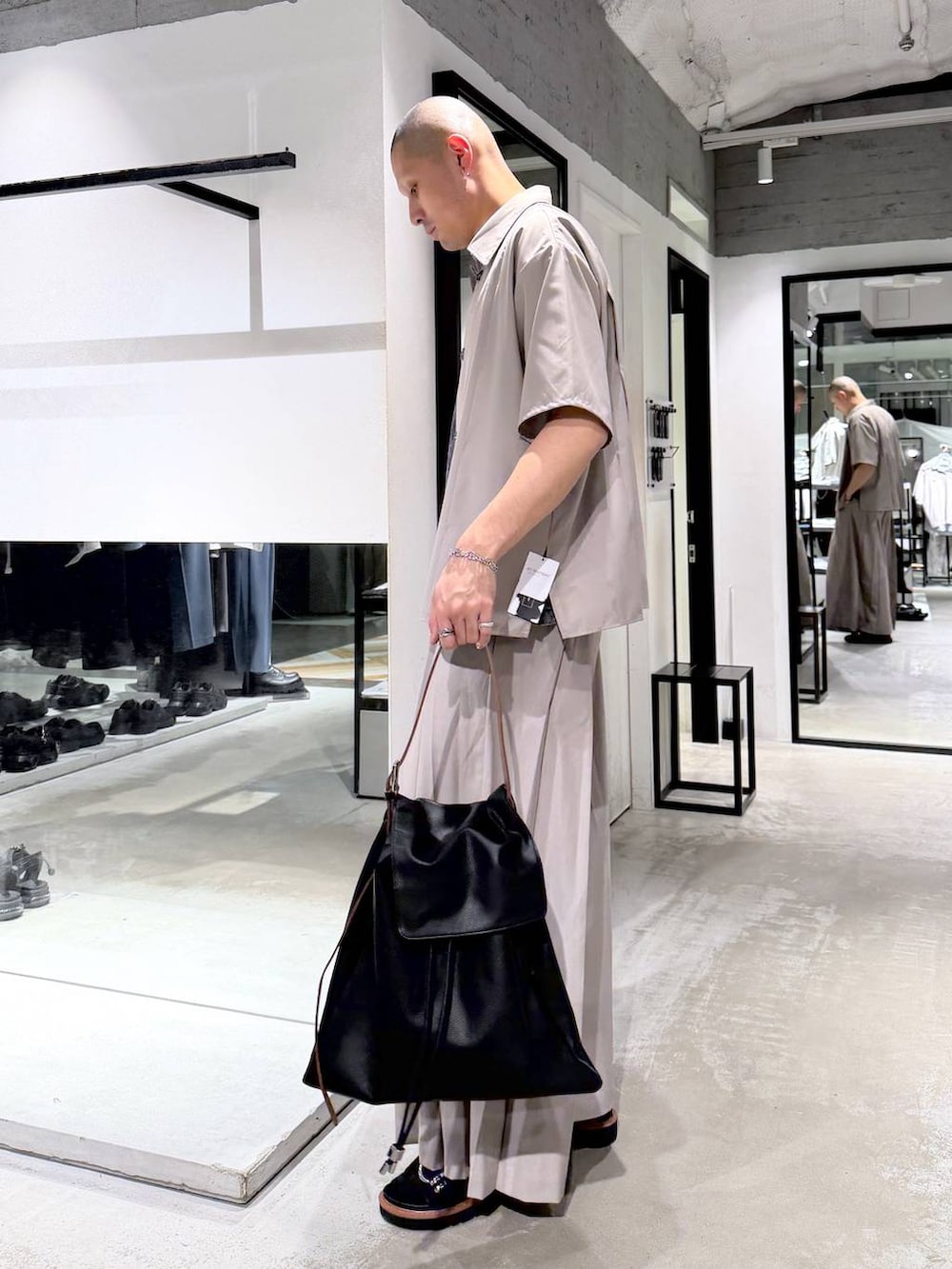 グレー系のTシャツ/カットソー、ブラウン系のサンダル、ブラック系のトートバッグを着用したメンズの春コーディネートの2枚目の写真