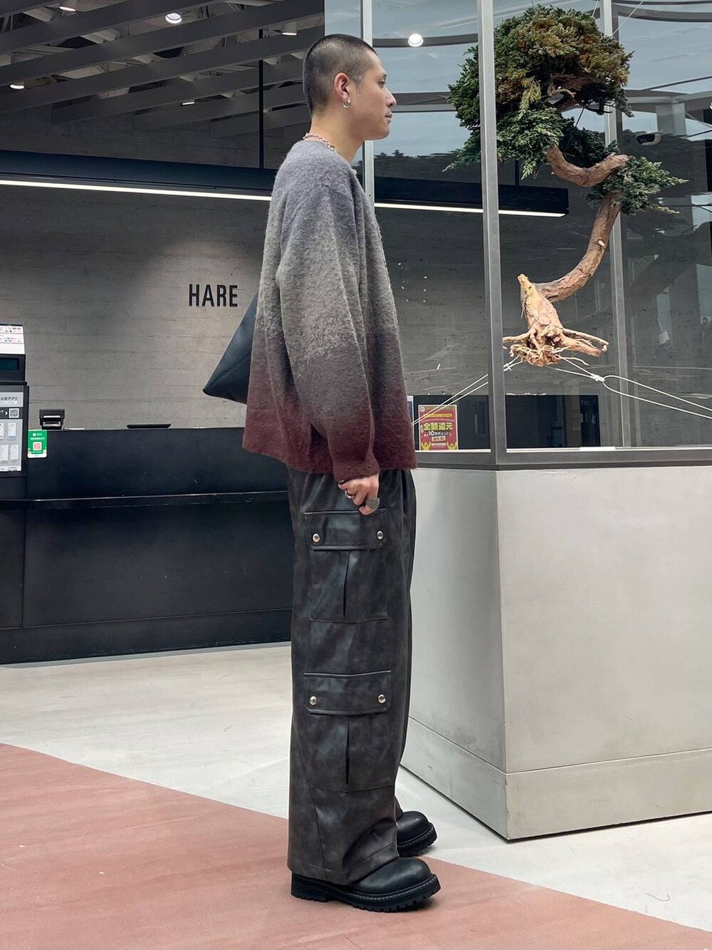 レッド系のカーディガン/ボレロ、グレー系のカーゴパンツ、ブラック系のブーツを着用したメンズの秋コーディネートの4枚目の写真