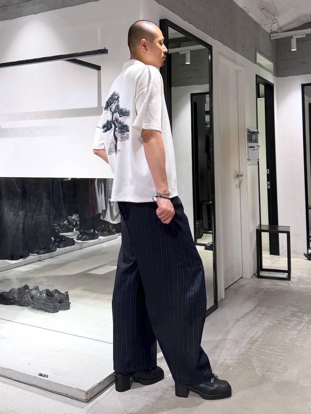 ホワイト系のTシャツ/カットソー、ブラック系のサンダル、ブルー系のスラックスを着用したメンズの夏コーディネートの4枚目の写真