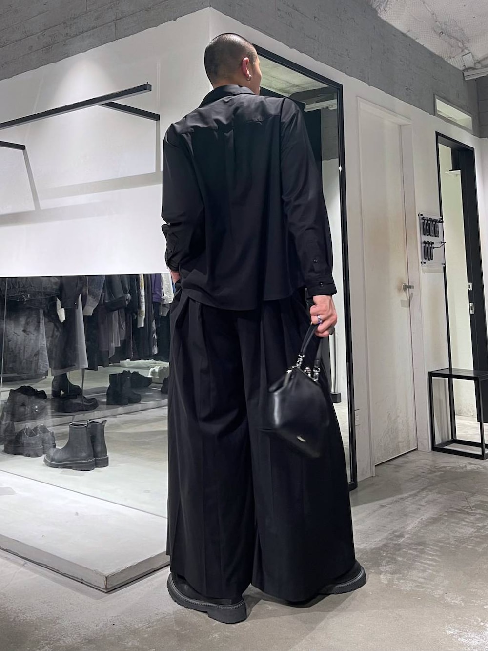 ブラック系のショルダーバッグ、ブラック系のブーツ、ブラック系のスラックスを着用したメンズの秋コーディネートの3枚目の写真