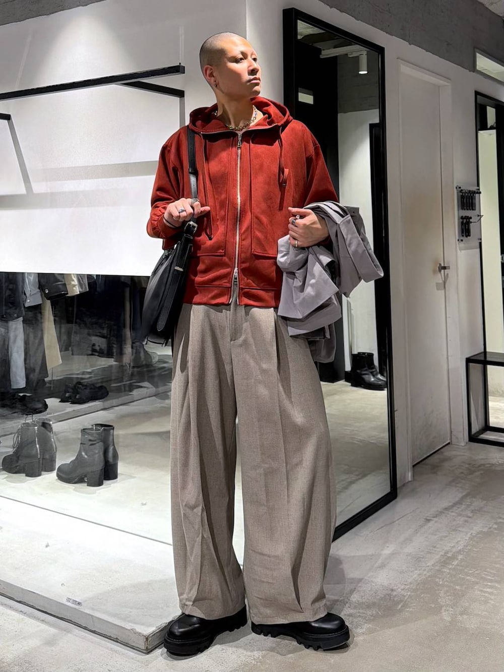 オレンジ系のパーカー、ブラック系のドレスシューズ、ブラック系のショルダーバッグを着用したメンズの春コーディネートの5枚目の写真