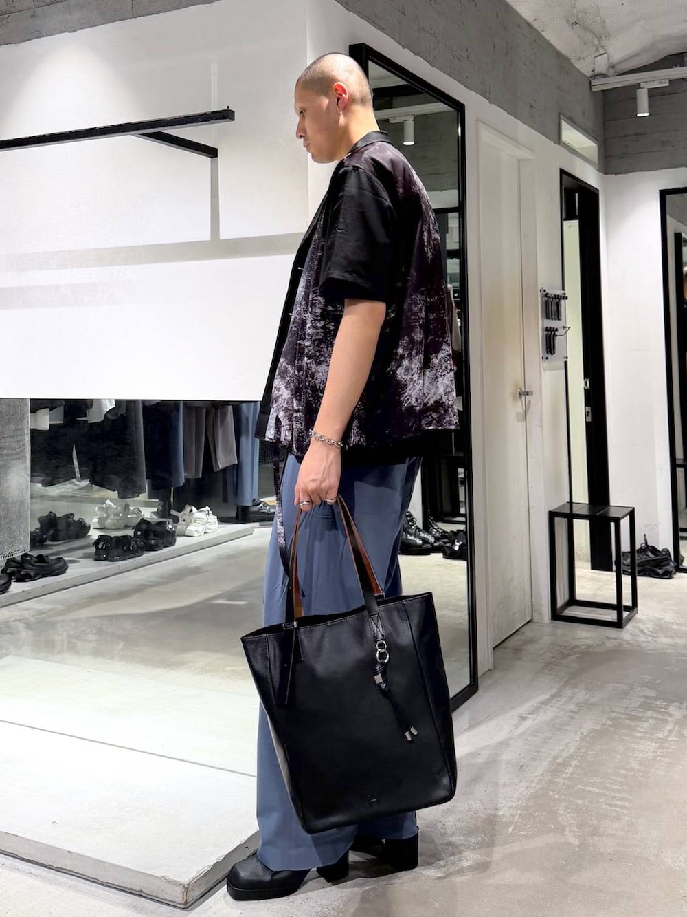 ブラック系のTシャツ/カットソー、ブラック系のサンダル、ブルー系のスラックスを着用したメンズの春コーディネートの2枚目の写真