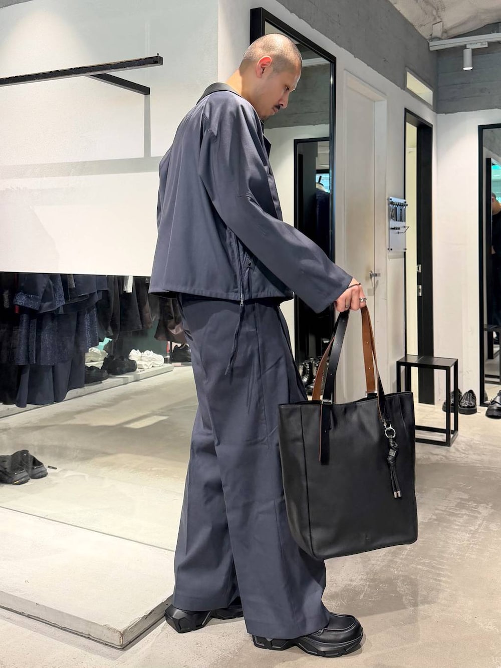 ブラック系のポロシャツ、ブルー系のスラックス、ブルー系のブルゾンを着用したメンズの秋コーディネートの4枚目の写真