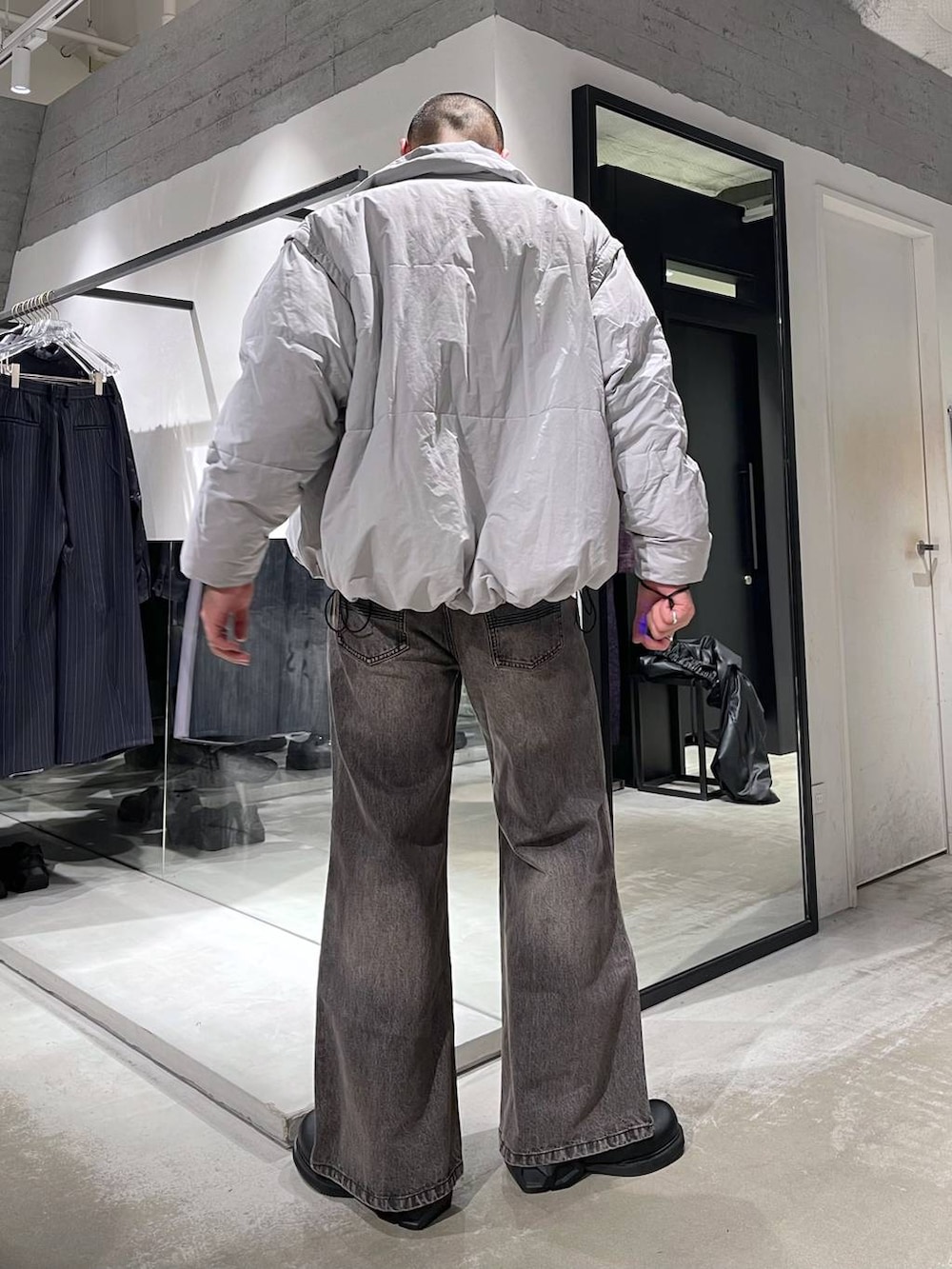 グレー系のダウンジャケット/コート、ブラウン系のデニムパンツ、ブラック系のドレスシューズを着用したメンズの冬コーディネートの3枚目の写真