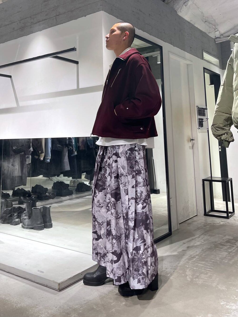 レッド系のブルゾン、ブラック系のトートバッグ、ブラック系のブーツを着用したメンズの秋コーディネートの2枚目の写真