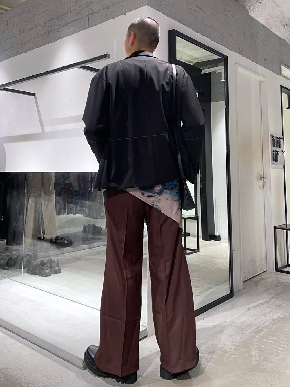 レッド系のスラックス、ブラック系のショルダーバッグ、ブラック系のドレスシューズを着用したメンズの冬コーディネートの3枚目の写真