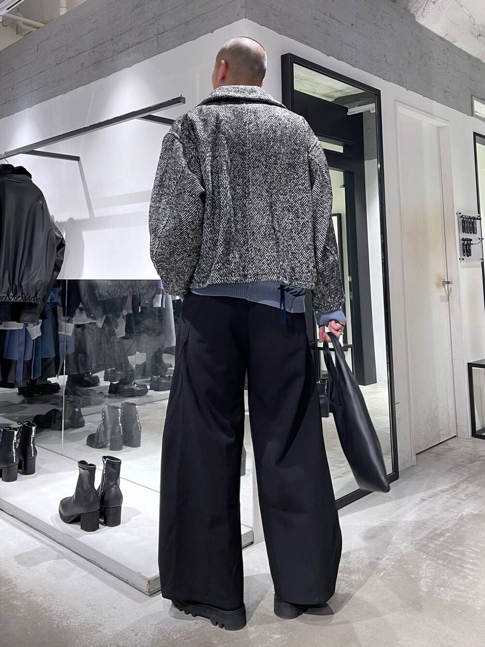 ブラック系のトートバッグ、グレー系のブルゾン、ブラック系のスラックスを着用したメンズの冬コーディネートの3枚目の写真