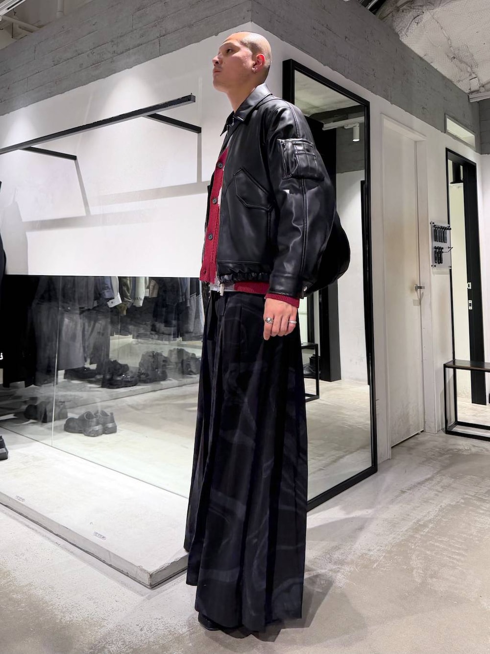 ブラック系のブルゾン、グレー系のその他パンツ、レッド系のカーディガン/ボレロを着用したメンズの冬コーディネートの2枚目の写真