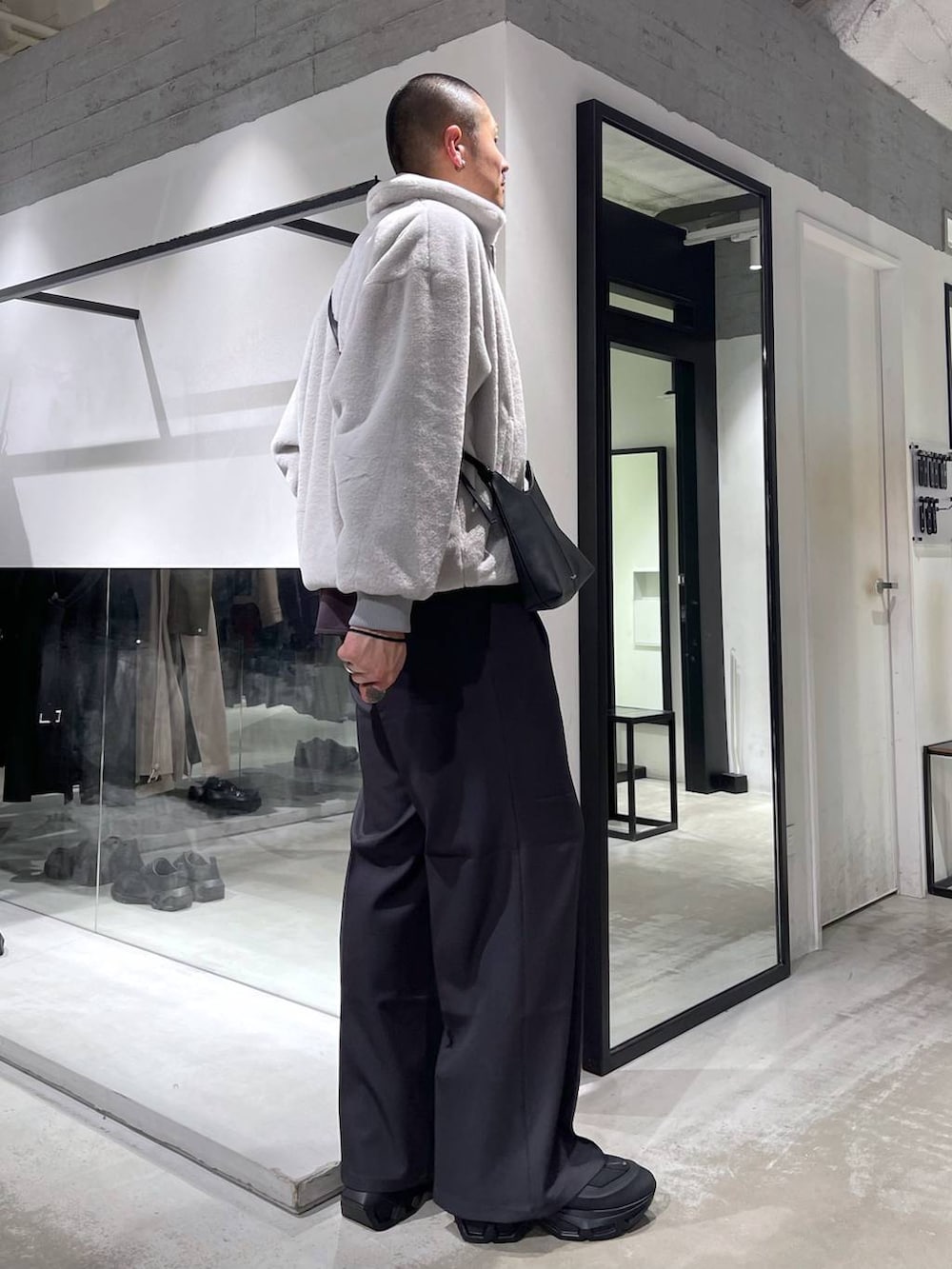 グレー系のブルゾン、グレー系のスラックス、ブラック系のショルダーバッグを着用したメンズの冬コーディネートの4枚目の写真