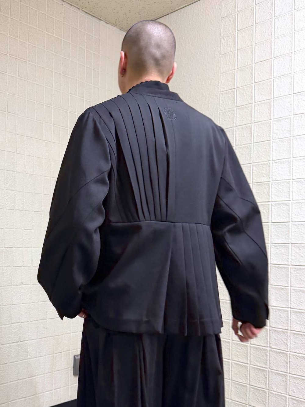 ブラック系のノーカラージャケットを着用したメンズの春コーディネートの6枚目の写真