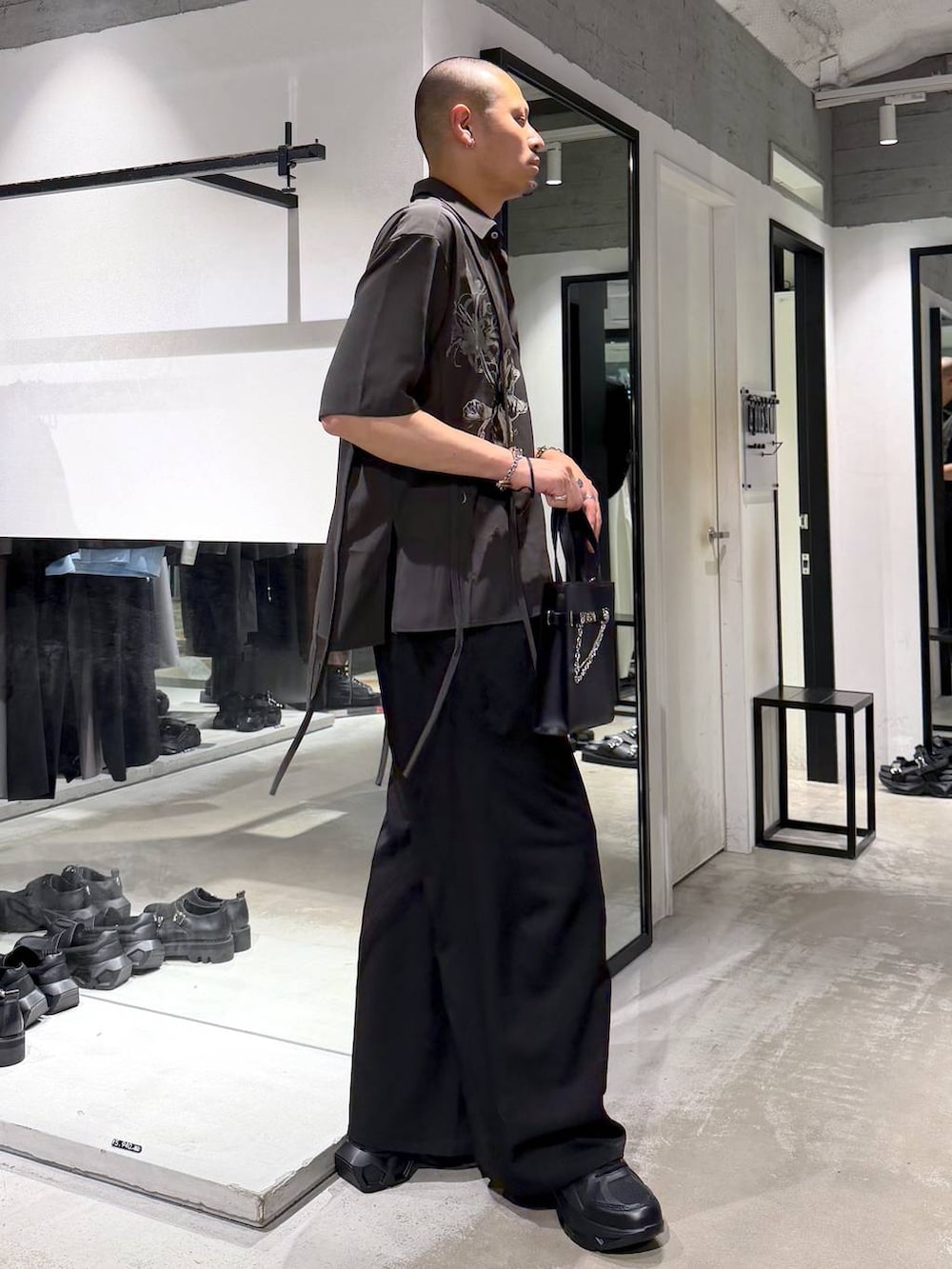 ブラック系のスニーカー、ブラック系のスラックス、ブラック系のショルダーバッグを着用したメンズの夏コーディネートの4枚目の写真