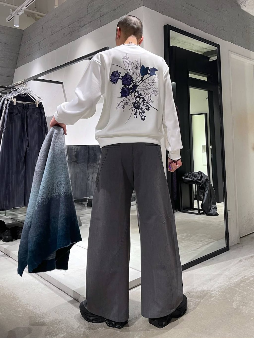 ブラック系のステンカラーコート、ブルー系のカーディガン/ボレロ、ブラック系のトートバッグを着用したメンズの冬コーディネートの6枚目の写真