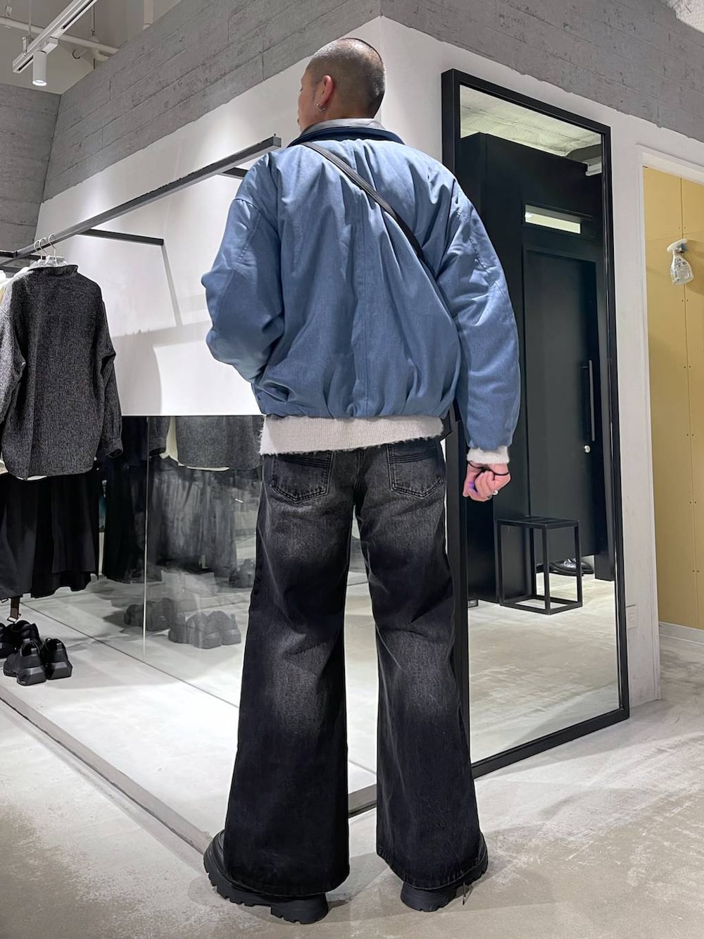 ブラック系のデニムパンツ、ブラック系のドレスシューズ、ブラック系のショルダーバッグを着用したメンズの冬コーディネートの3枚目の写真