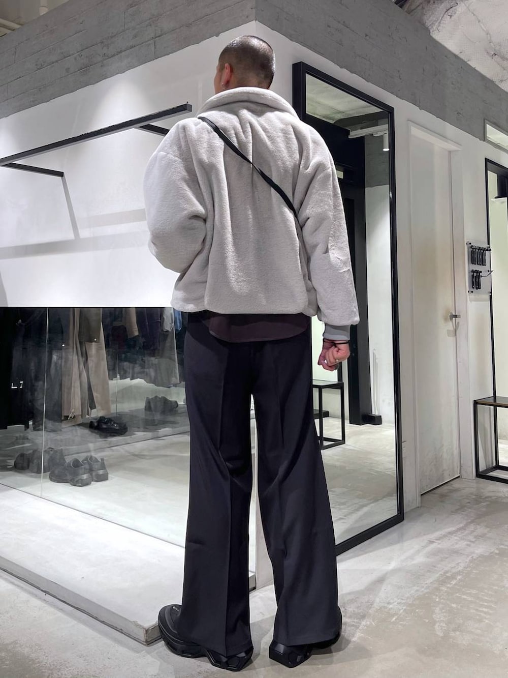 グレー系のブルゾン、グレー系のスラックス、ブラック系のショルダーバッグを着用したメンズの冬コーディネートの3枚目の写真