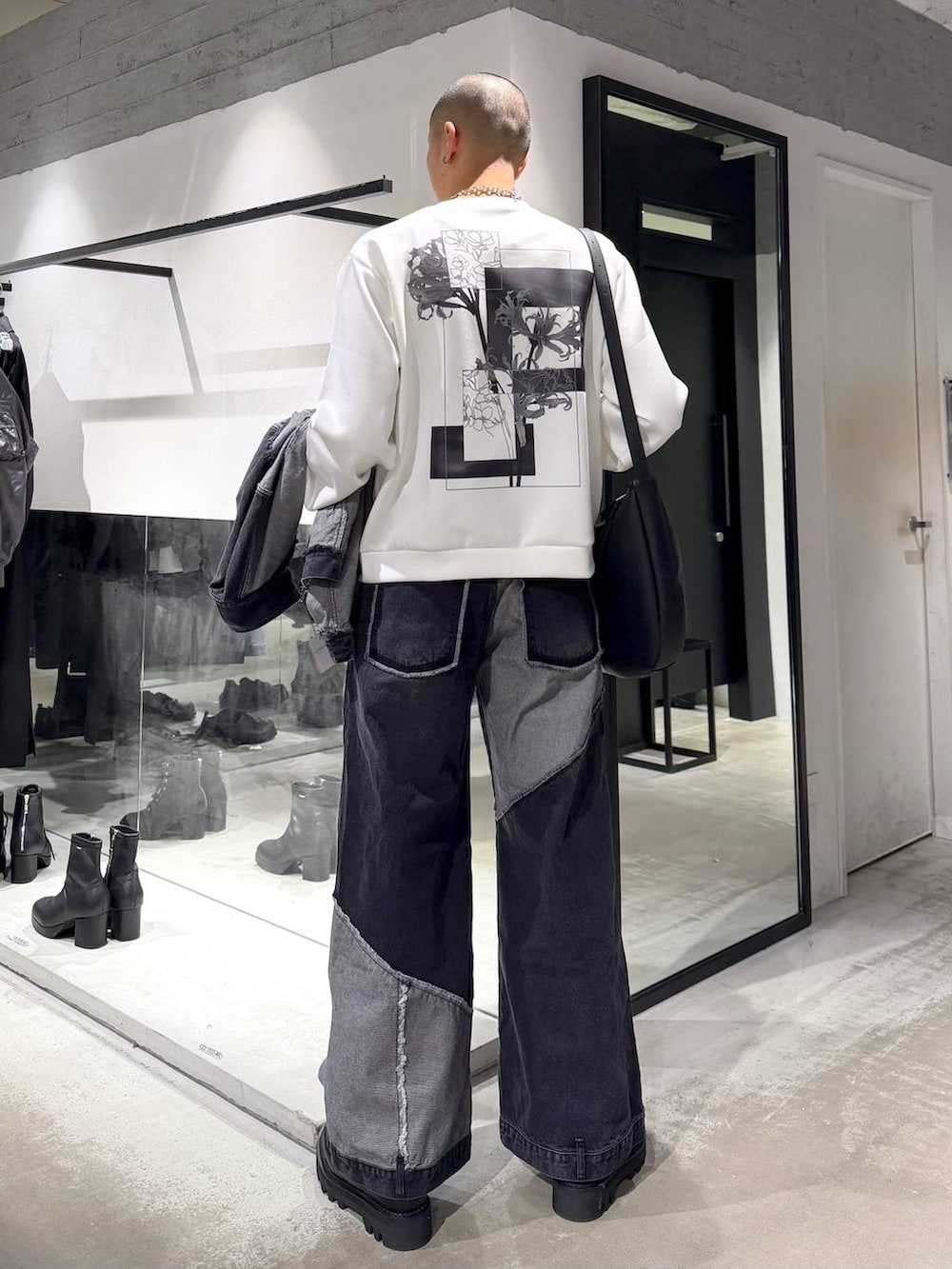 ブラック系のデニムパンツ、ブラック系のドレスシューズ、ブラック系のショルダーバッグを着用したメンズの冬コーディネートの6枚目の写真