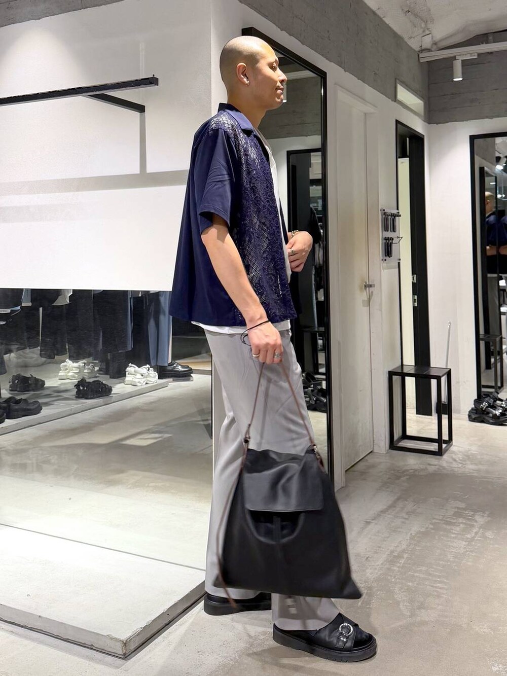 グレー系のスラックス、ブラック系のサンダル、ブラック系のトートバッグを着用したメンズの春コーディネートの4枚目の写真