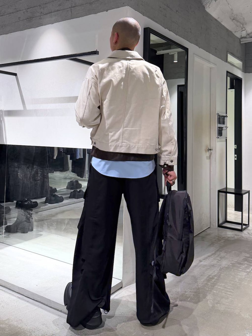 ホワイト系のデニムジャケット、ブラック系のバックパック/リュック、ブラック系のカーゴパンツを着用したメンズの春コーディネートの3枚目の写真
