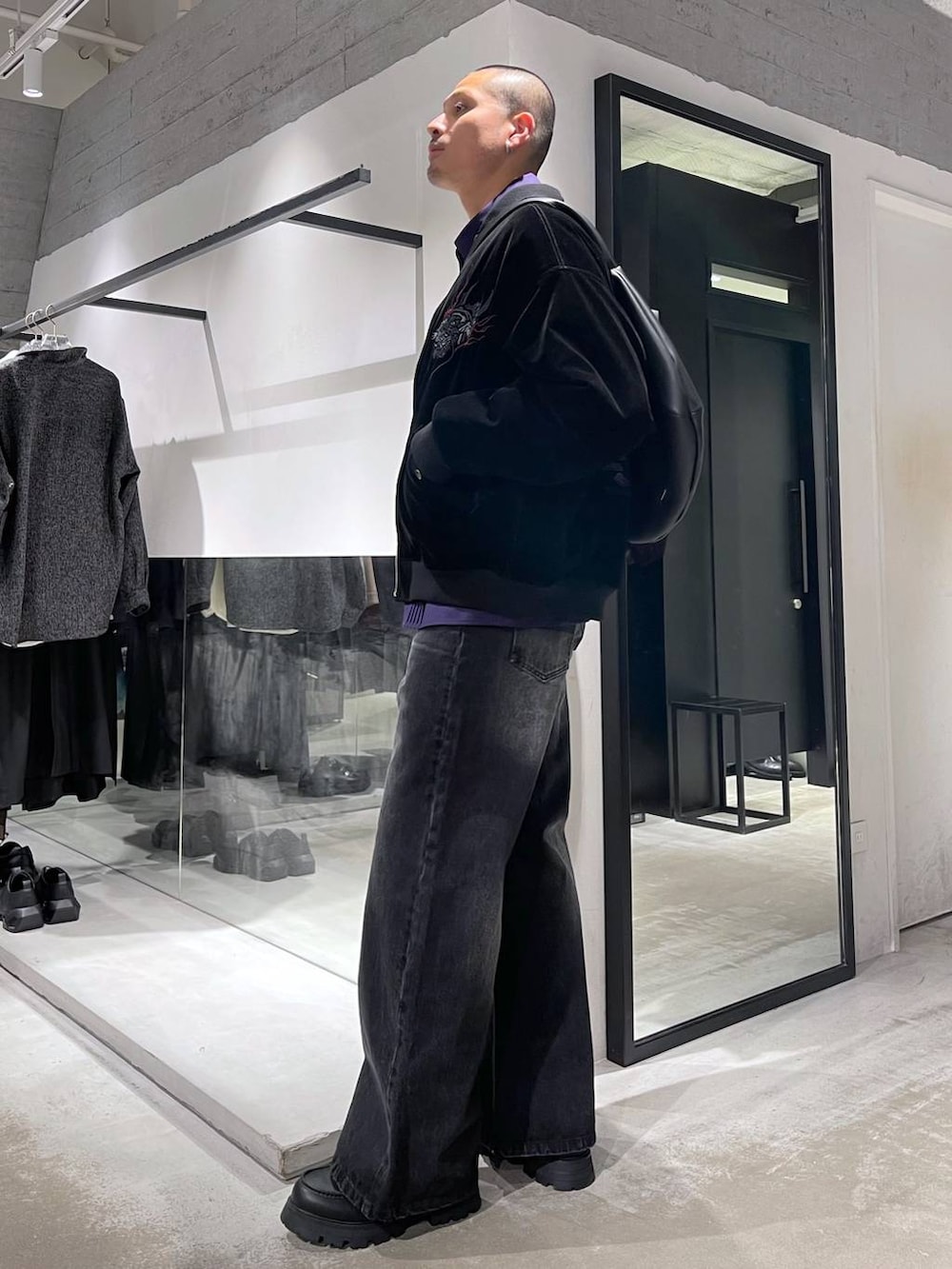 ブラック系のデニムパンツ、ブラック系のドレスシューズ、ブラック系のショルダーバッグを着用したメンズの冬コーディネートの2枚目の写真