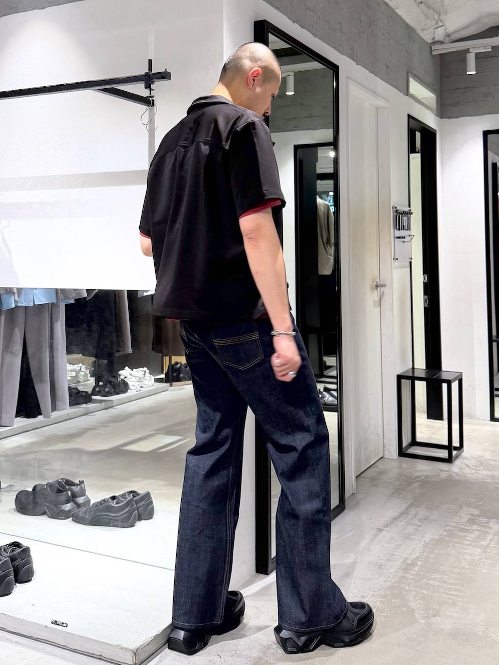 ブラック系のスニーカー、レッド系のTシャツ/カットソー、ブルー系のデニムパンツを着用したメンズの夏コーディネートの5枚目の写真