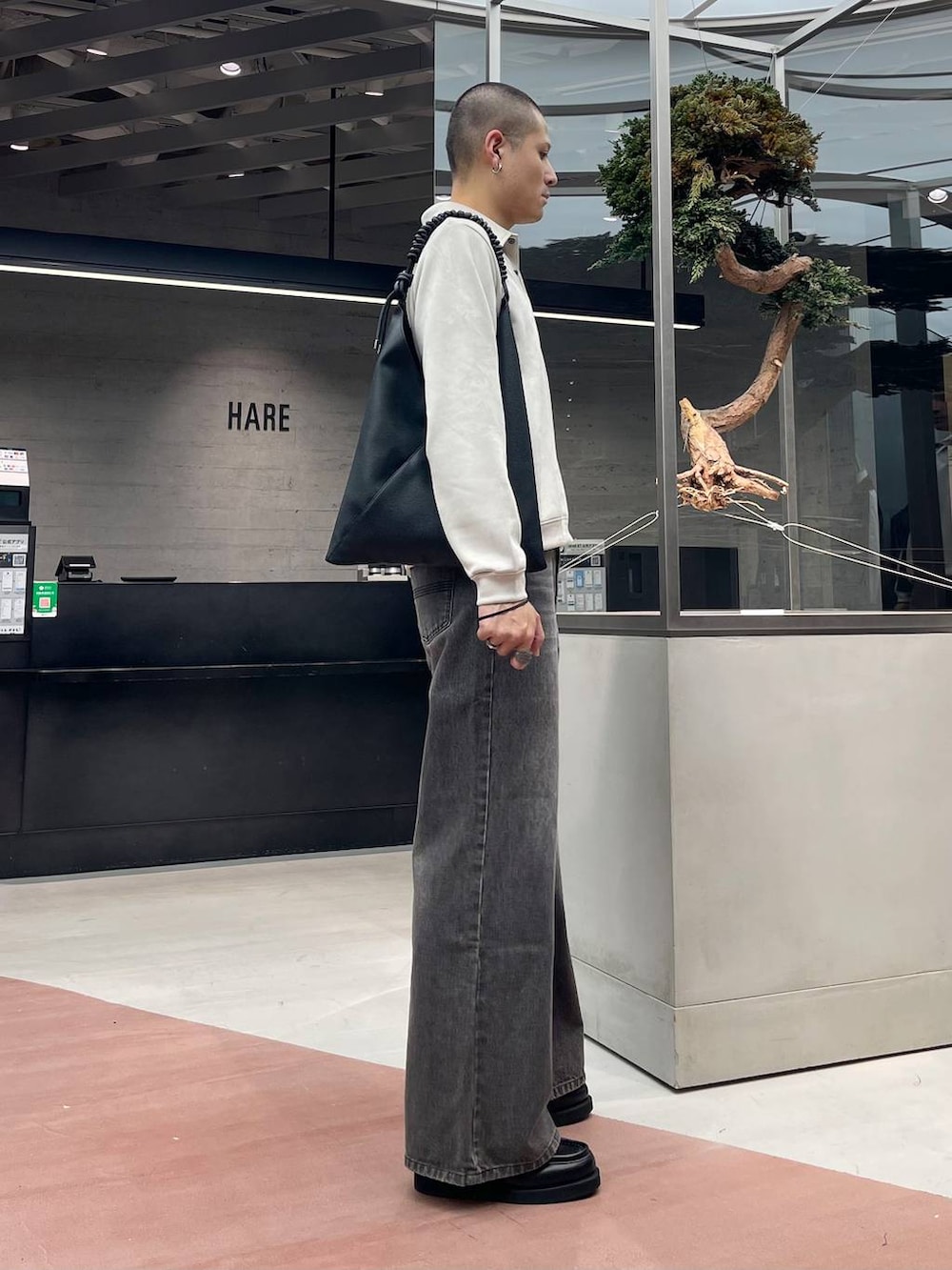 ブラック系のローファー、ブラウン系のデニムパンツ、ブラック系のトートバッグを着用したメンズの秋コーディネートの4枚目の写真