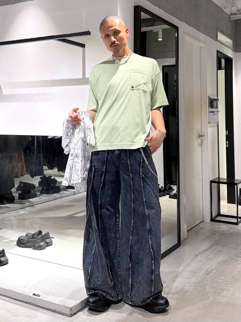 ブラック系のスニーカー、ブルー系のデニムパンツ、グリーン系のTシャツ/カットソーを着用したメンズの夏コーディネートの5枚目の写真