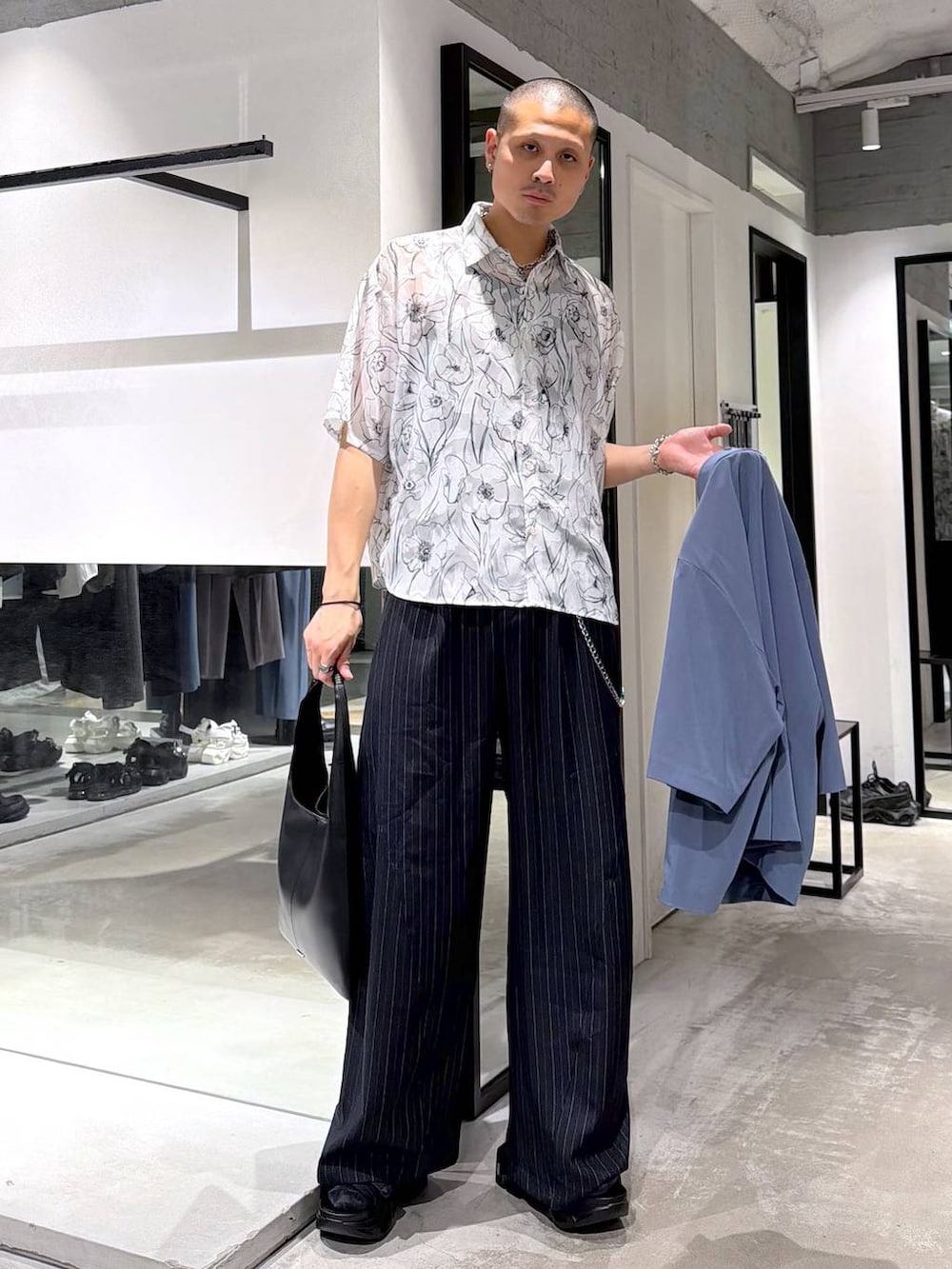 ブラック系のトートバッグ、ブラック系のサンダル、ブルー系のスラックスを着用したメンズの春コーディネートの6枚目の写真