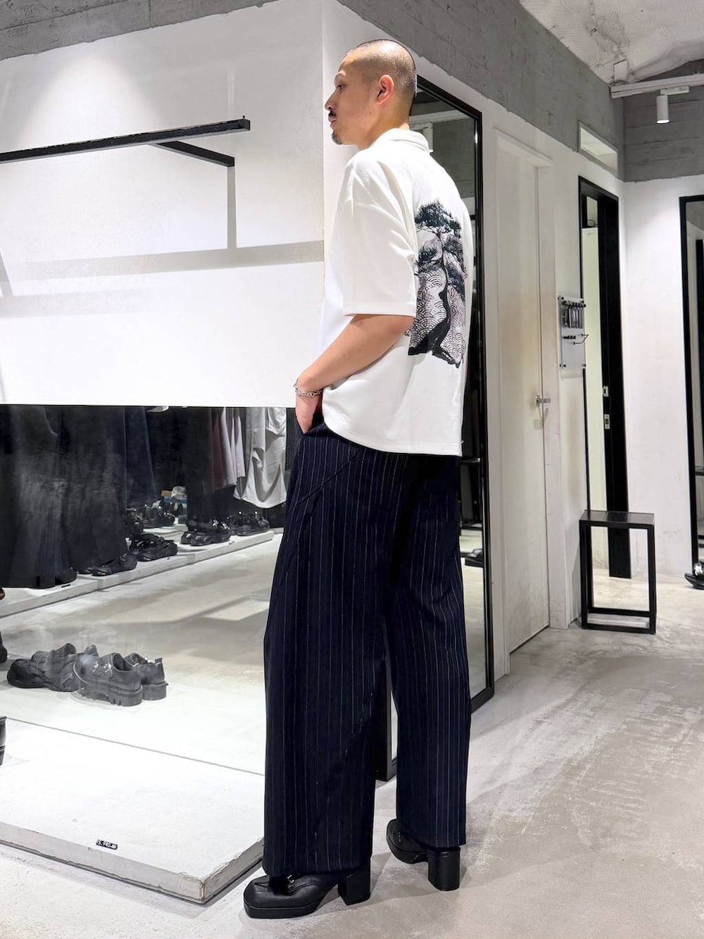 ホワイト系のTシャツ/カットソー、ブラック系のサンダル、ブルー系のスラックスを着用したメンズの夏コーディネートの2枚目の写真