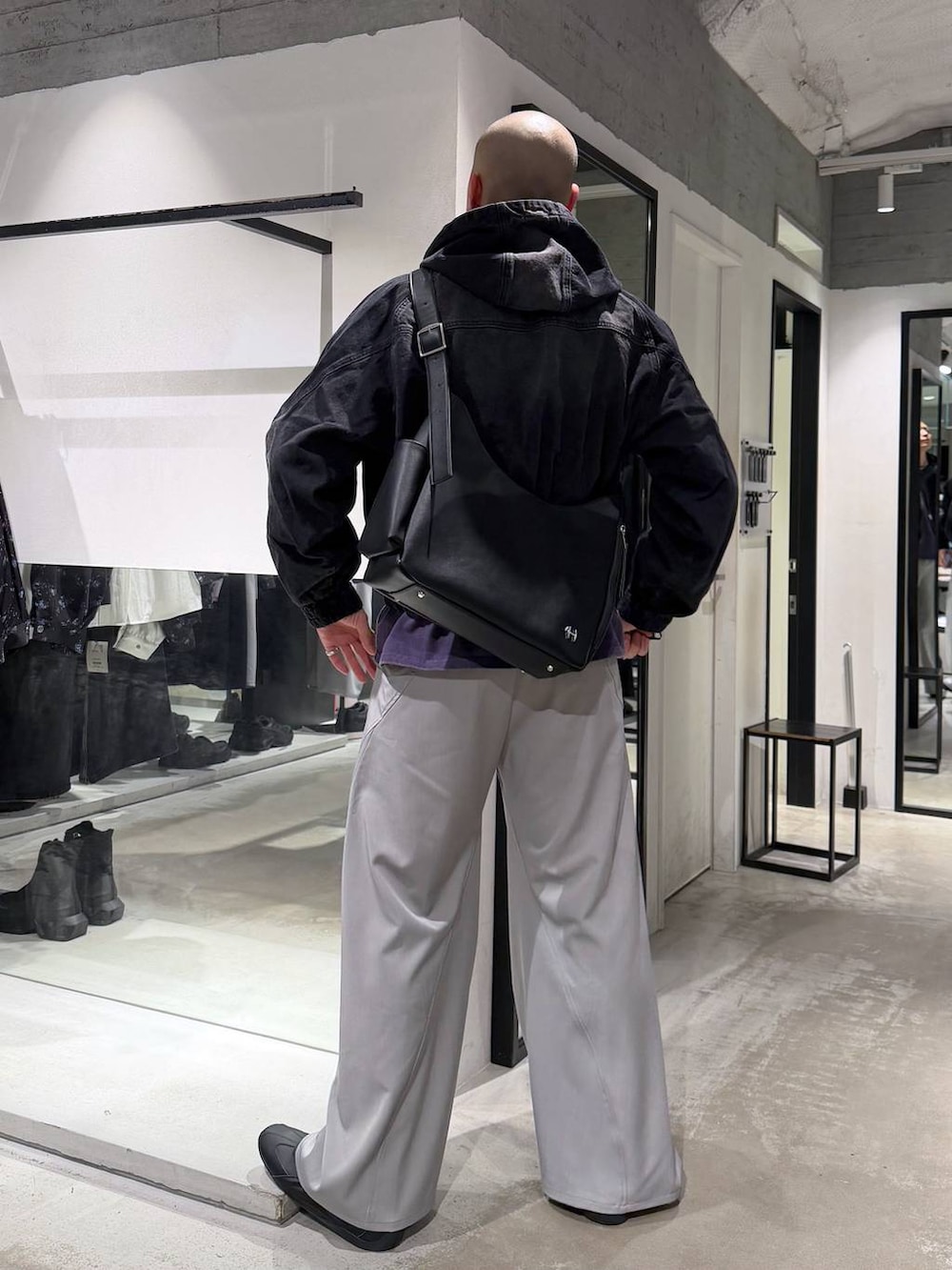 ブラック系のブルゾン、グレー系のスラックス、ブラック系のショルダーバッグを着用したメンズの春コーディネートの3枚目の写真