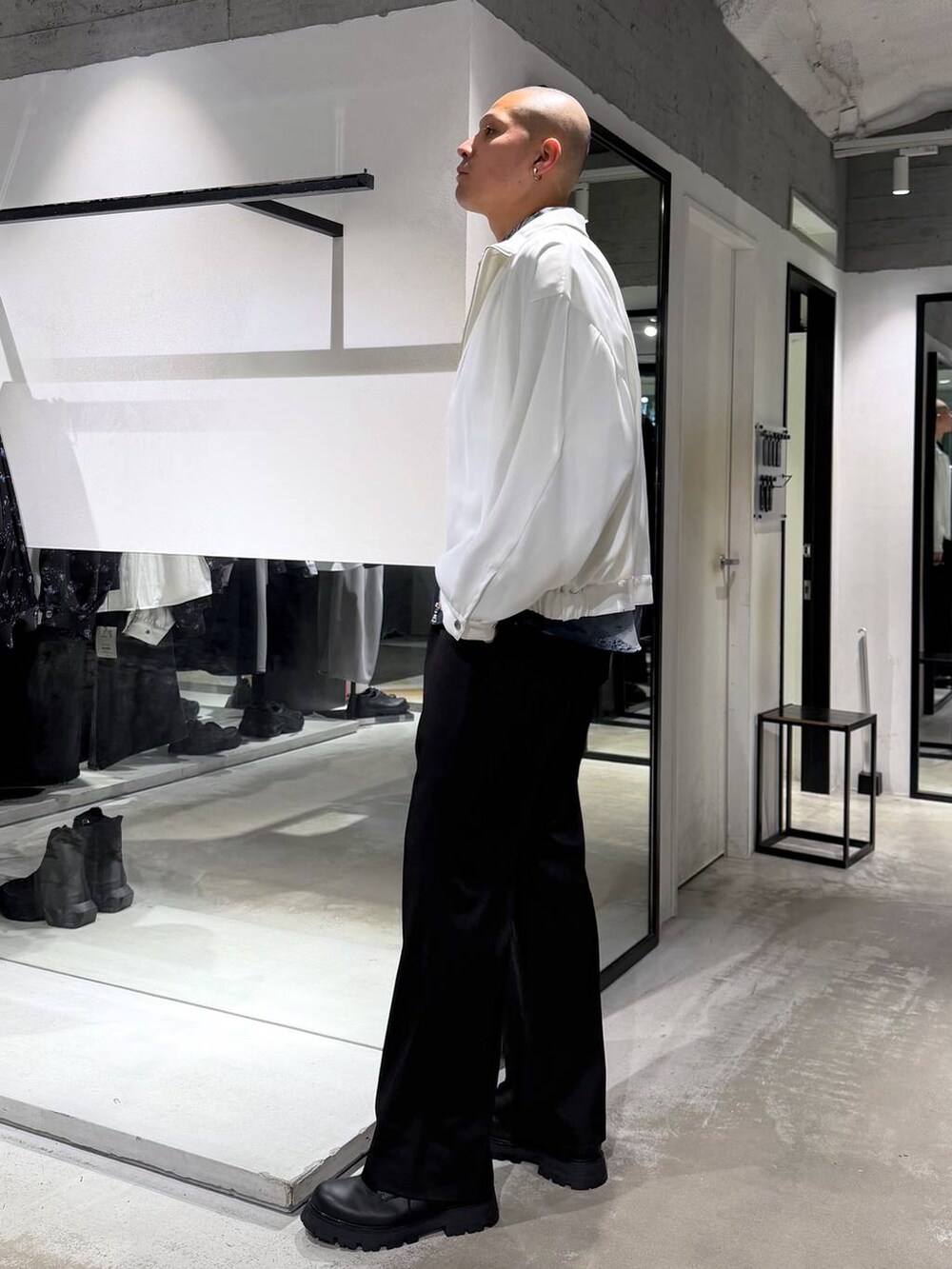 ブラック系のスラックス、ブラック系のドレスシューズ、ホワイト系のブルゾンを着用したメンズの春コーディネートの2枚目の写真