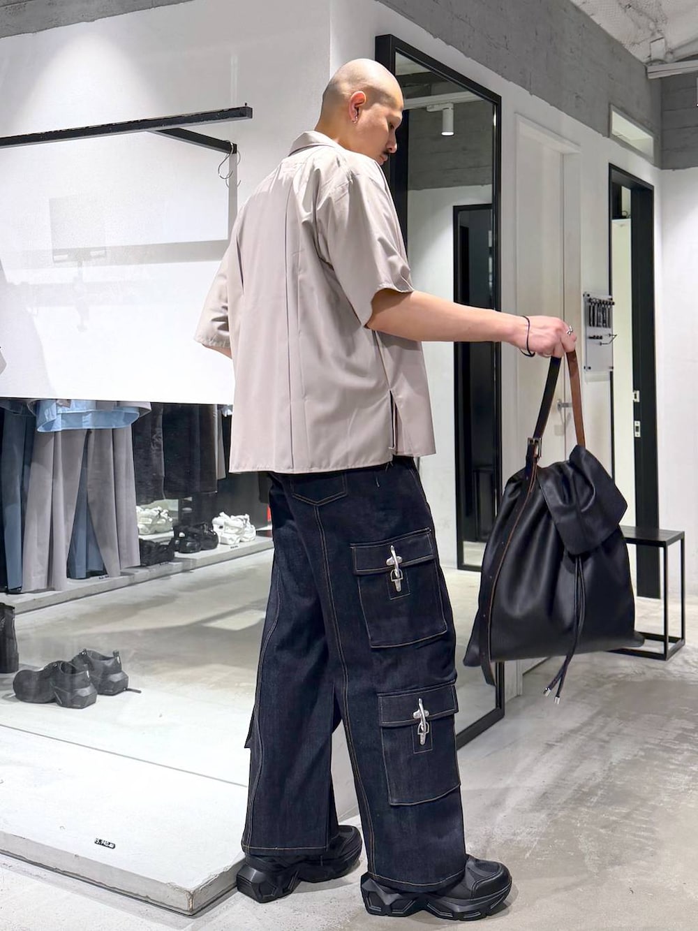 ブラック系のスニーカー、ブルー系のデニムパンツ、ブラック系のトートバッグを着用したメンズの夏コーディネートの4枚目の写真